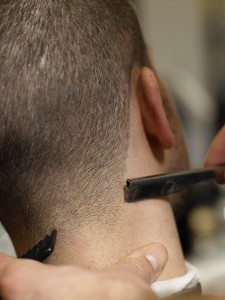 Barber giving man haircut, close-up, rear view